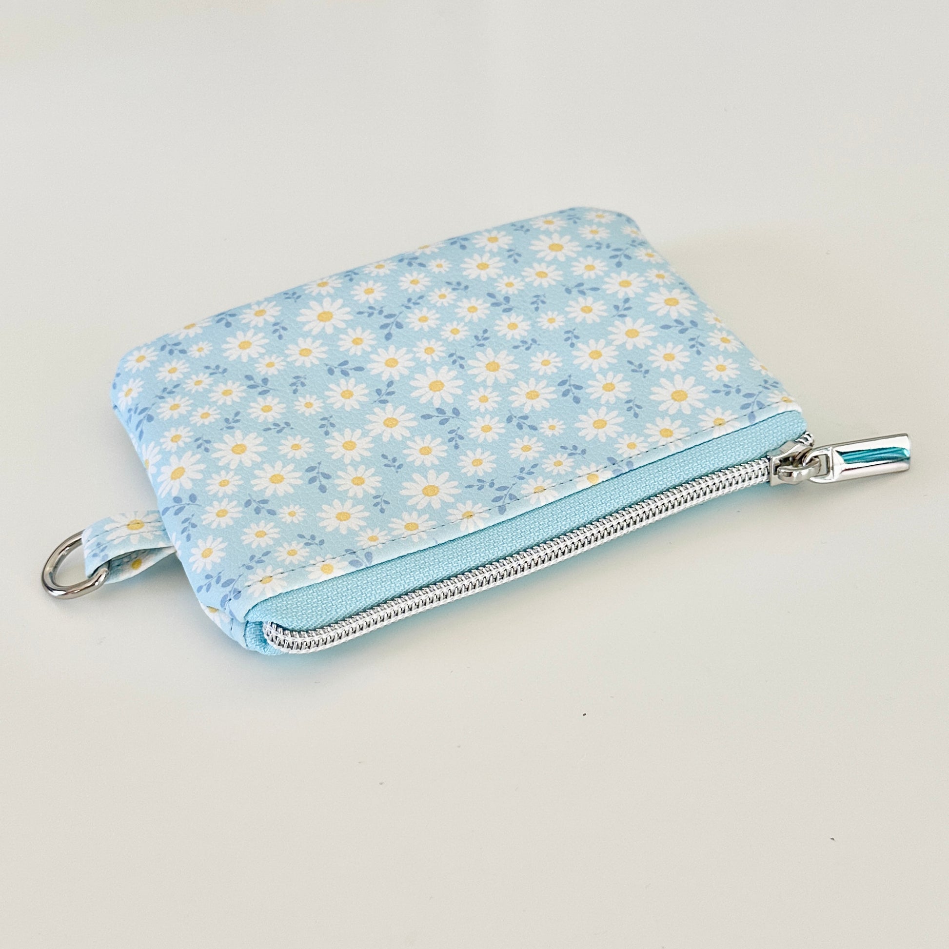 blue daisy Floral-patterned coin purse  with coins and cards on a light background