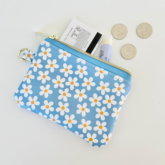 Blue floral daisy patterned coin purse with coins and cards on a white background