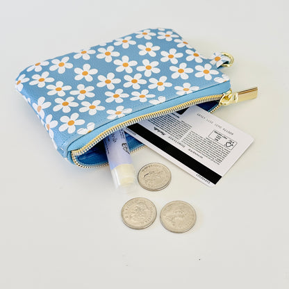 Blue floral daisy patterned coin purse with coins and cards on a white background