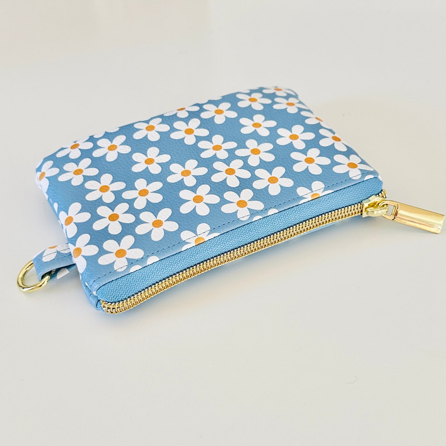 Blue floral daisy patterned coin purse with coins and cards on a white background