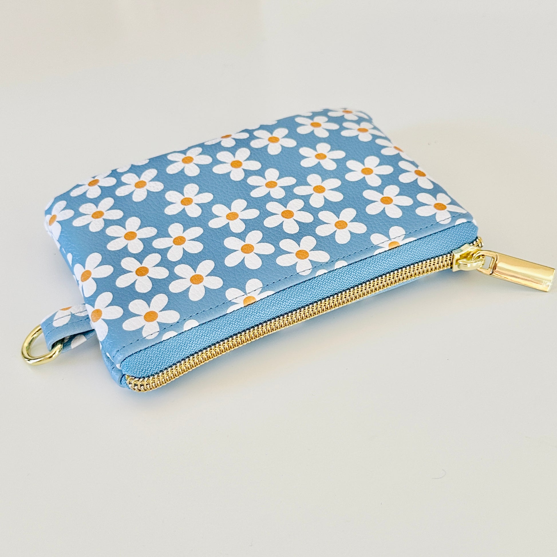 Blue floral daisy patterned coin purse with coins and cards on a white background