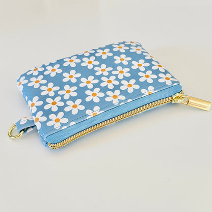 Blue floral daisy patterned coin purse with coins and cards on a white background