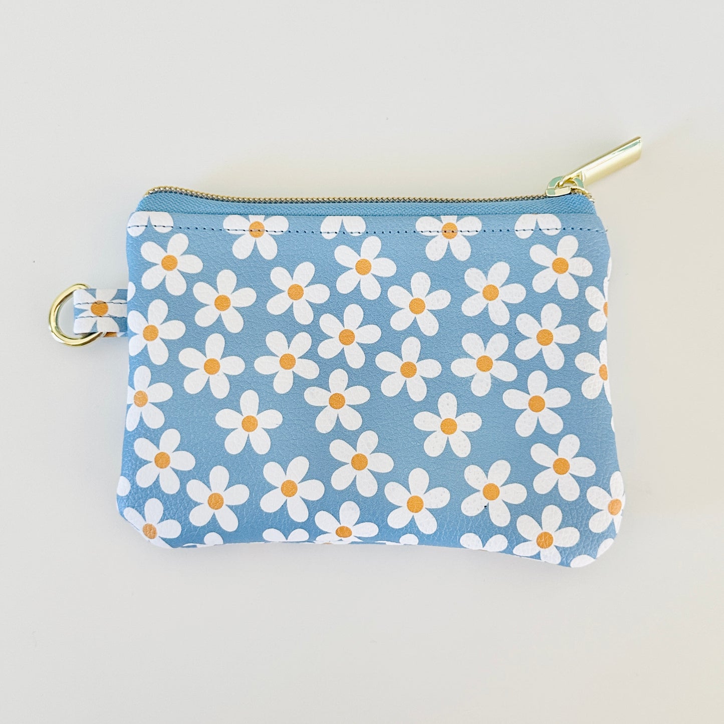Blue floral daisy patterned coin purse with coins and cards on a white background