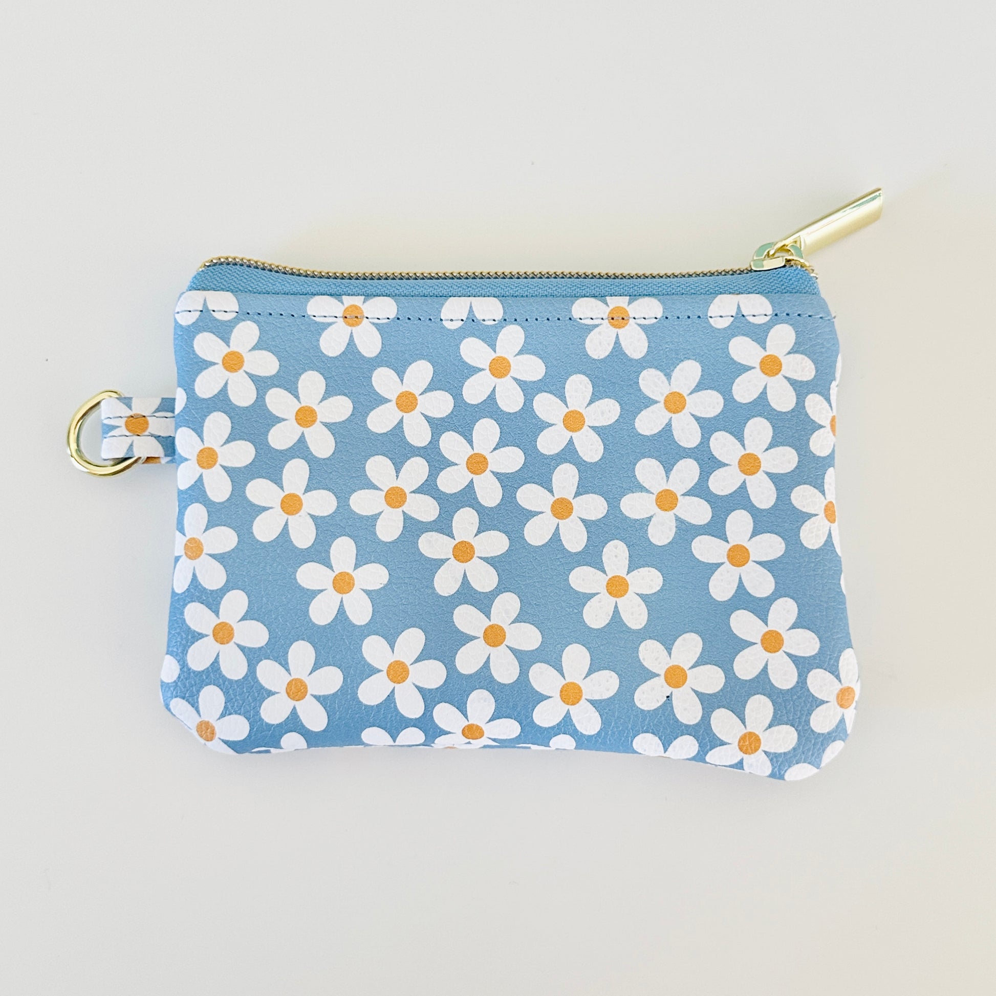 Blue floral daisy patterned coin purse with coins and cards on a white background