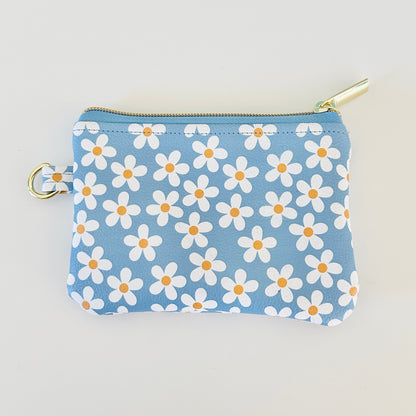 Blue floral daisy patterned coin purse with coins and cards on a white background