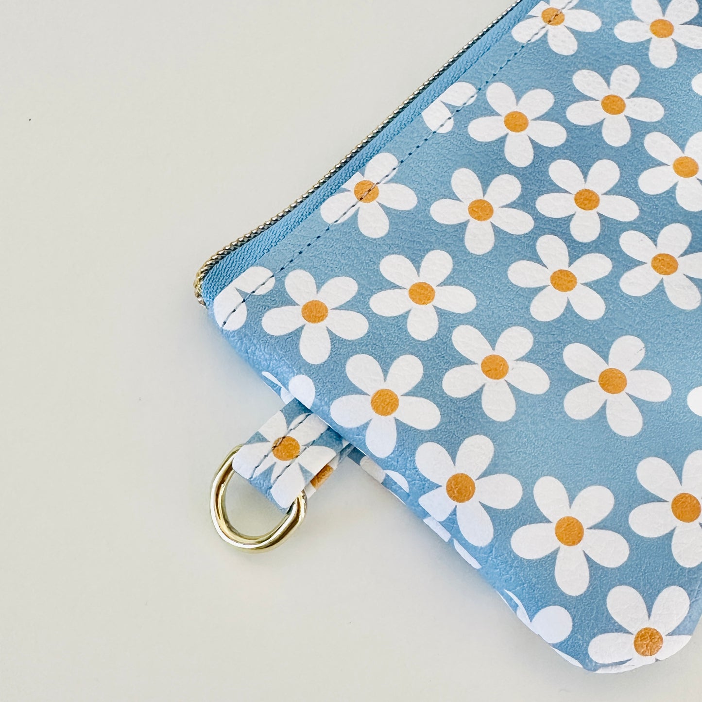 Blue floral daisy patterned coin purse with coins and cards on a white background