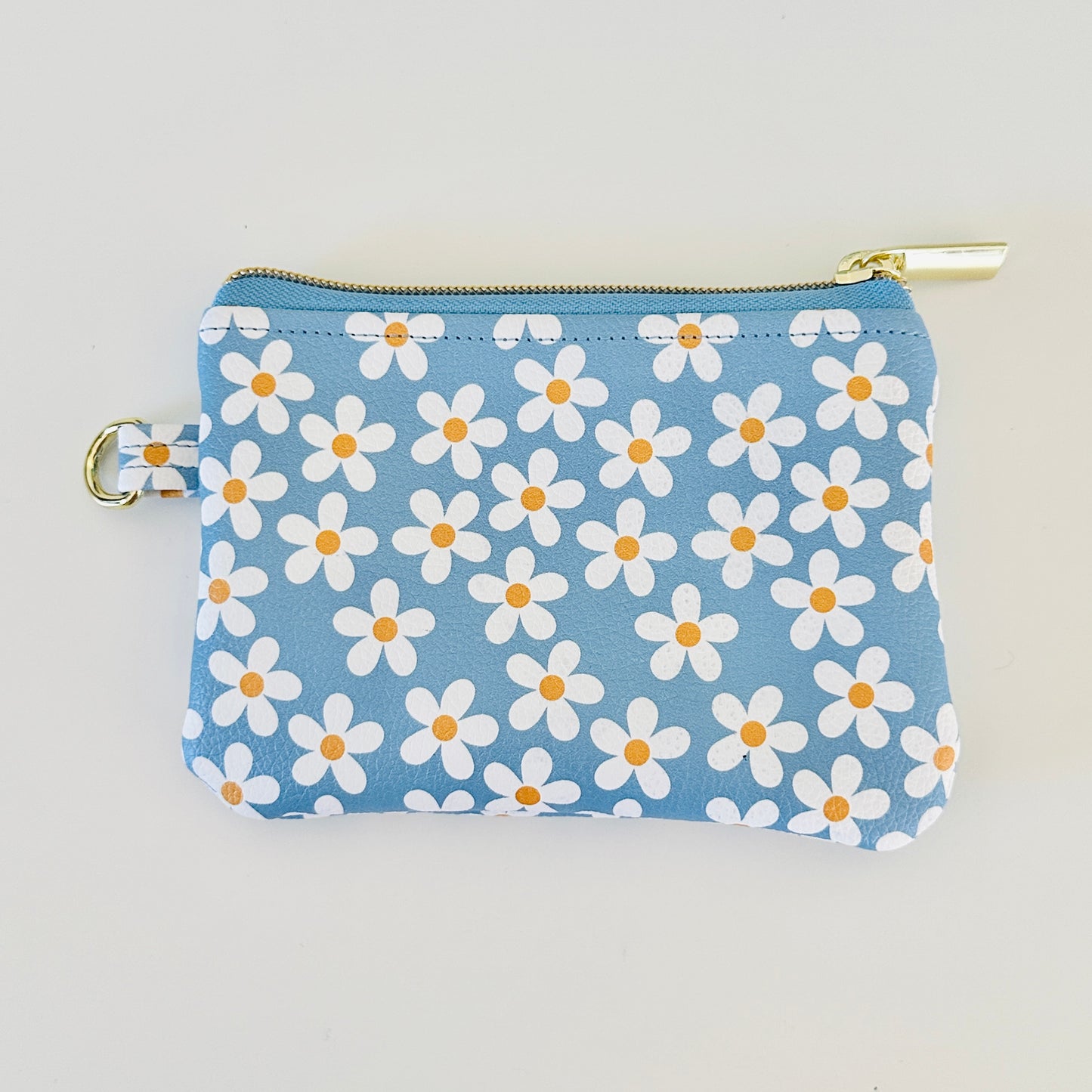 Blue floral daisy patterned coin purse with coins and cards on a white background