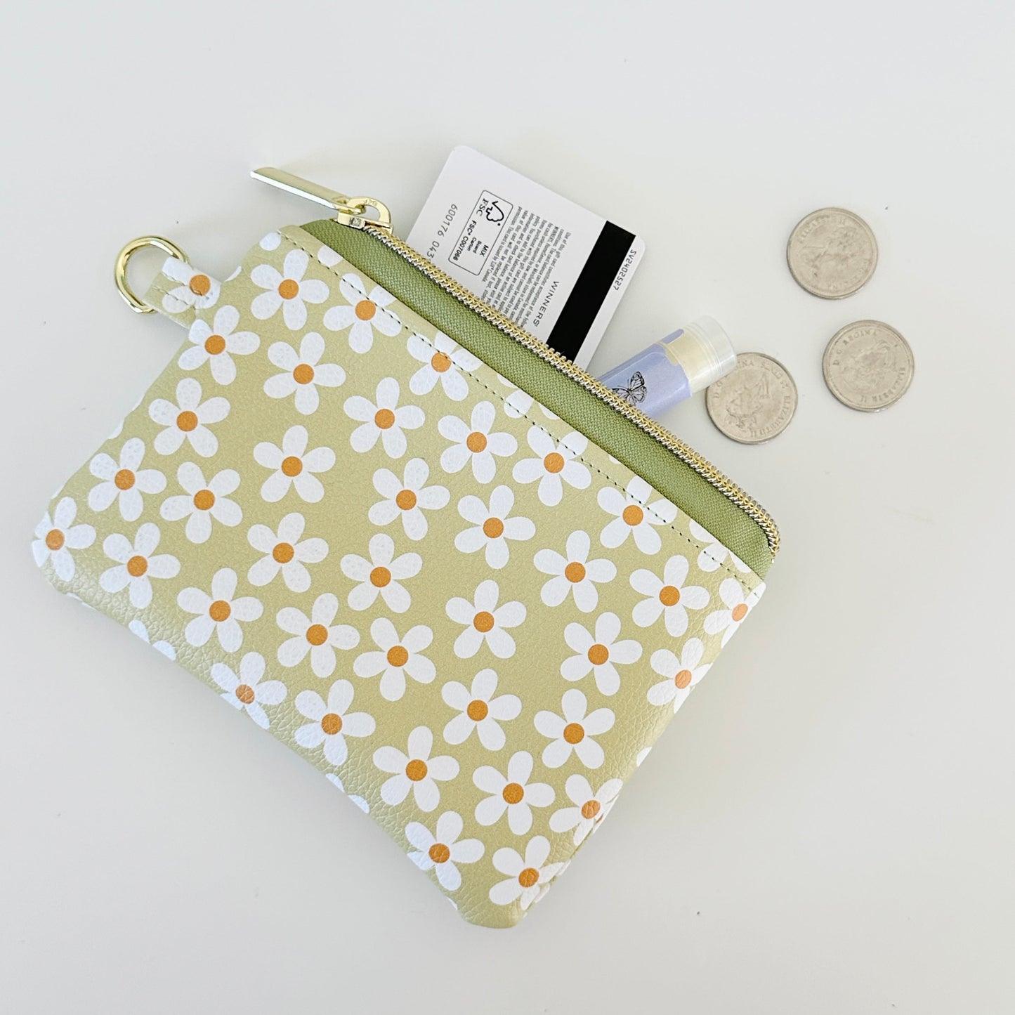 green Floral daisy patterned coin purse with coins on a light background