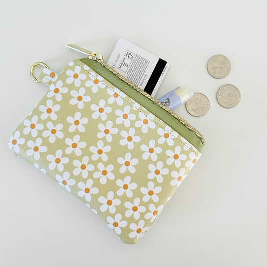 green Floral daisy patterned coin purse with coins on a light background