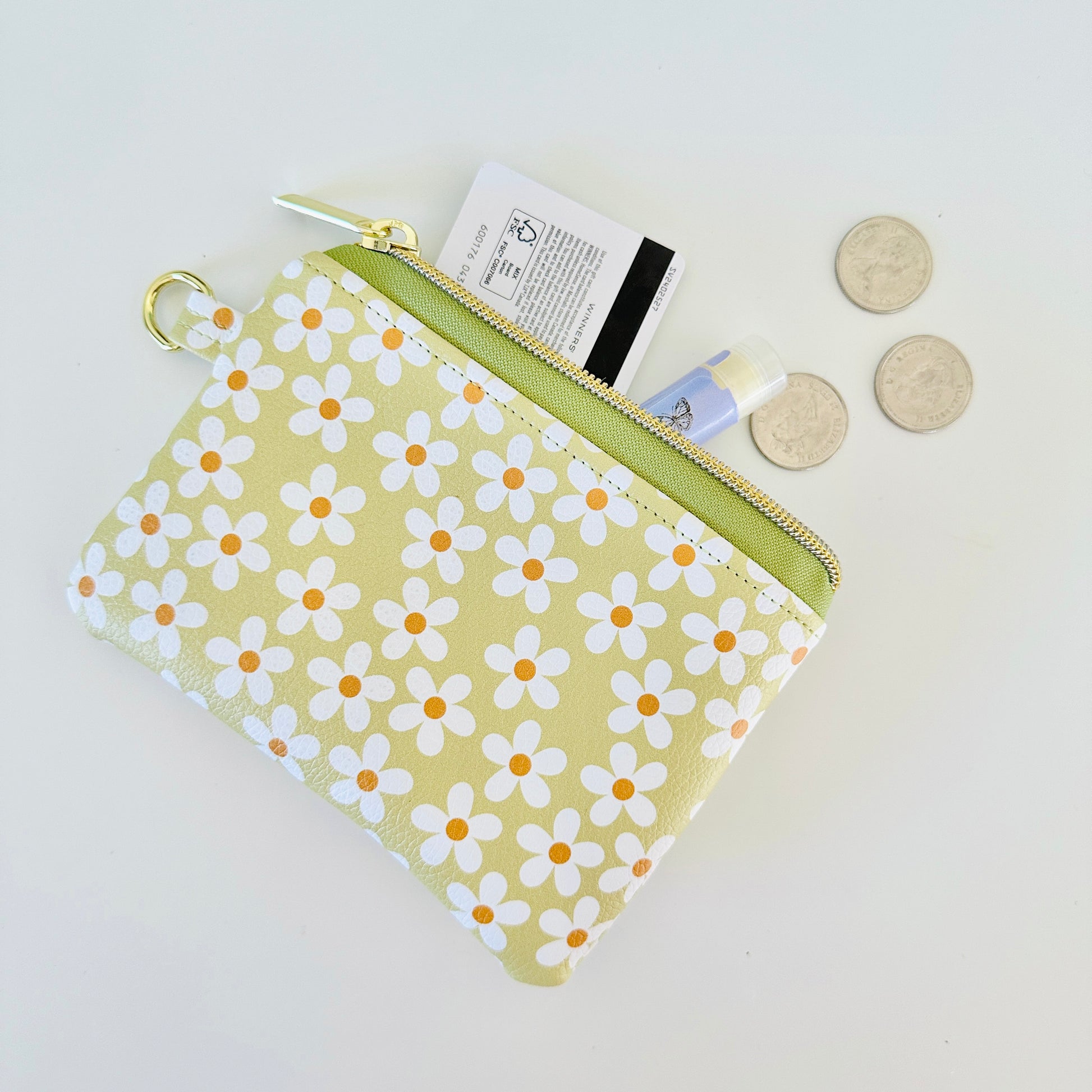 green Floral daisy patterned coin purse with coins on a light background