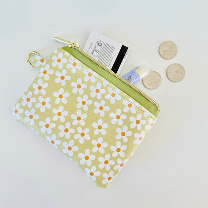 green Floral daisy patterned coin purse with coins on a light background