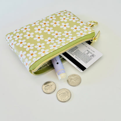 green Floral daisy patterned coin purse with coins on a light background