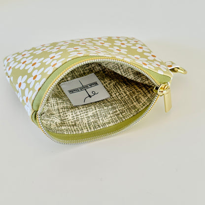 green Floral daisy patterned coin purse with coins on a light background