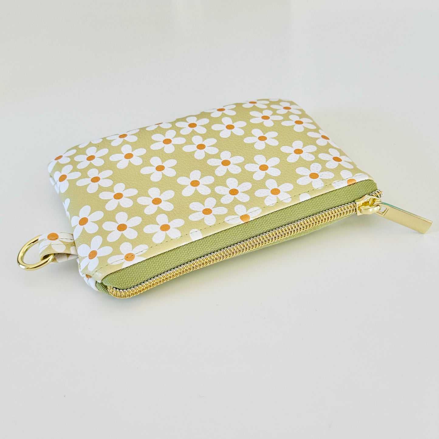 green Floral daisy patterned coin purse with coins on a light background