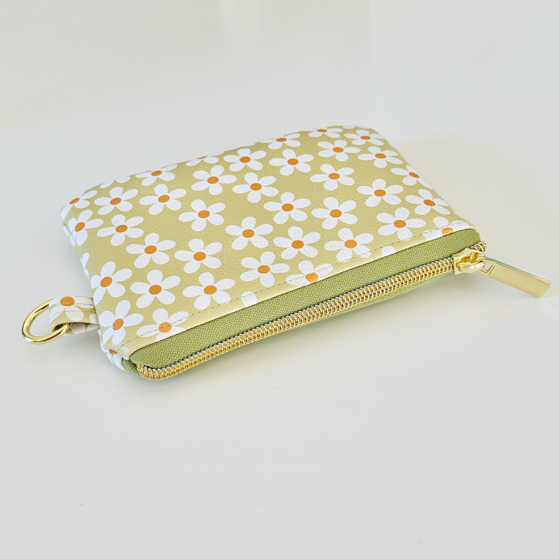 green Floral daisy patterned coin purse with coins on a light background