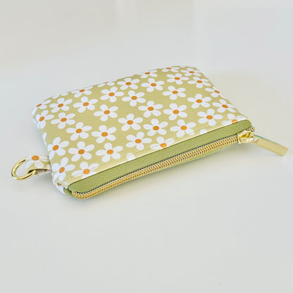 green Floral daisy patterned coin purse with coins on a light background