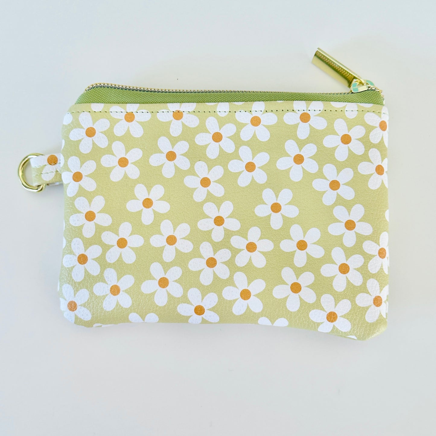 green Floral daisy patterned coin purse with coins on a light background
