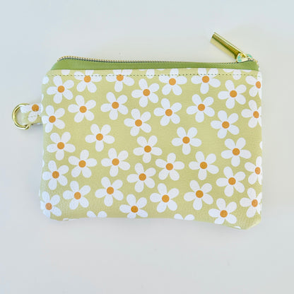 green Floral daisy patterned coin purse with coins on a light background