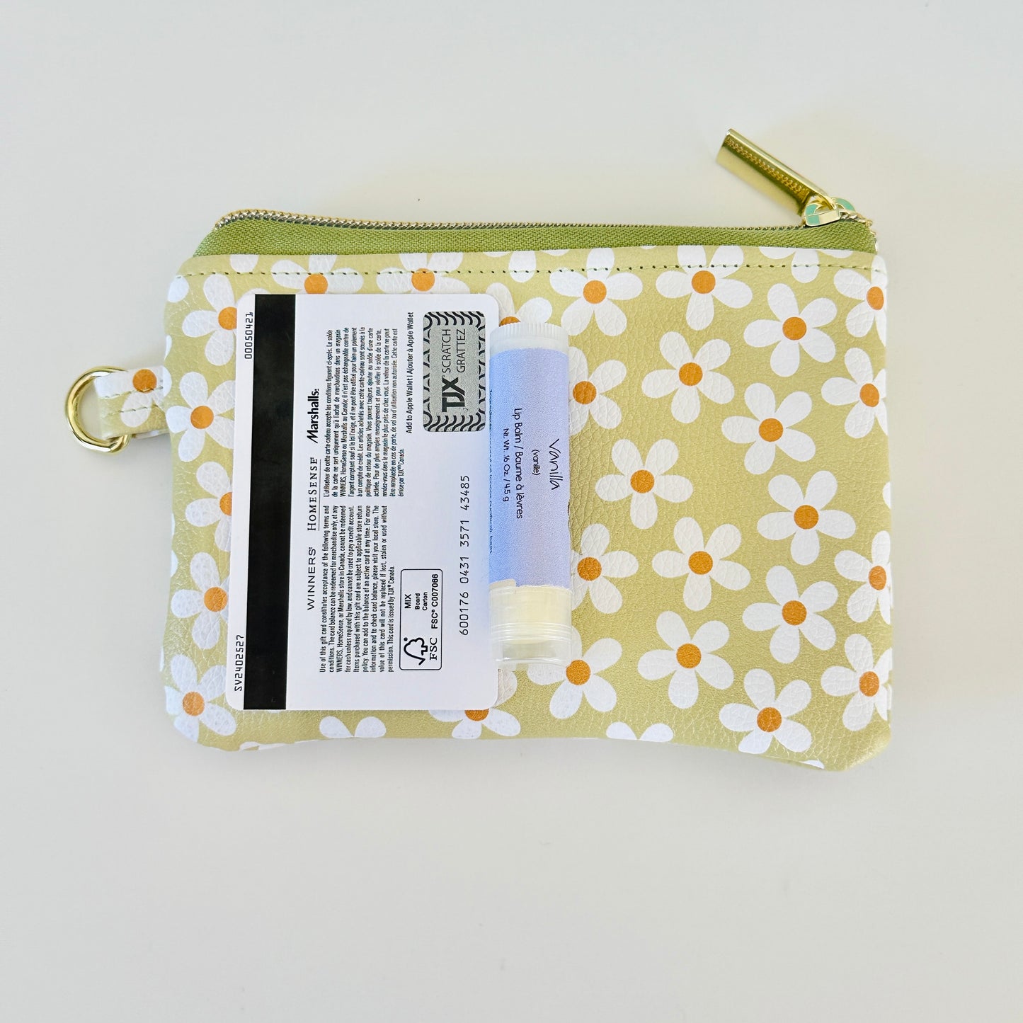 green Floral daisy patterned coin purse with coins on a light background