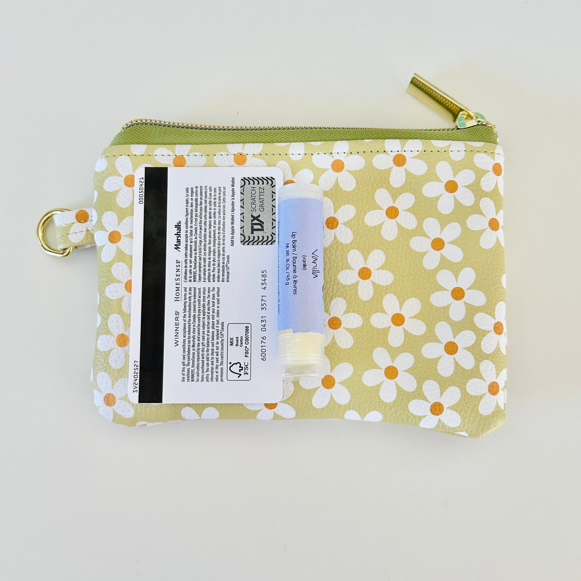 green Floral daisy patterned coin purse with coins on a light background