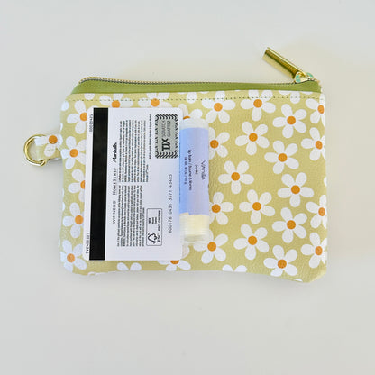 green Floral daisy patterned coin purse with coins on a light background