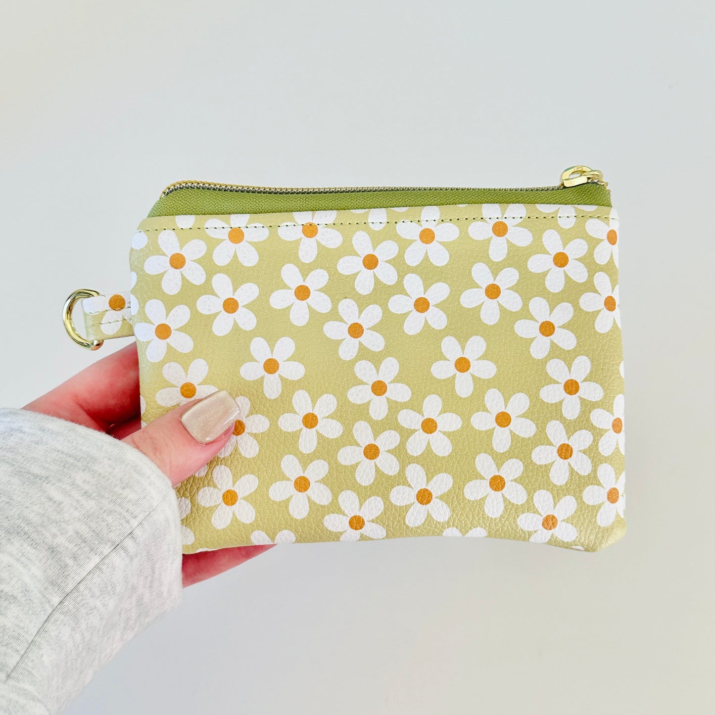 green Floral daisy patterned coin purse with coins on a light background