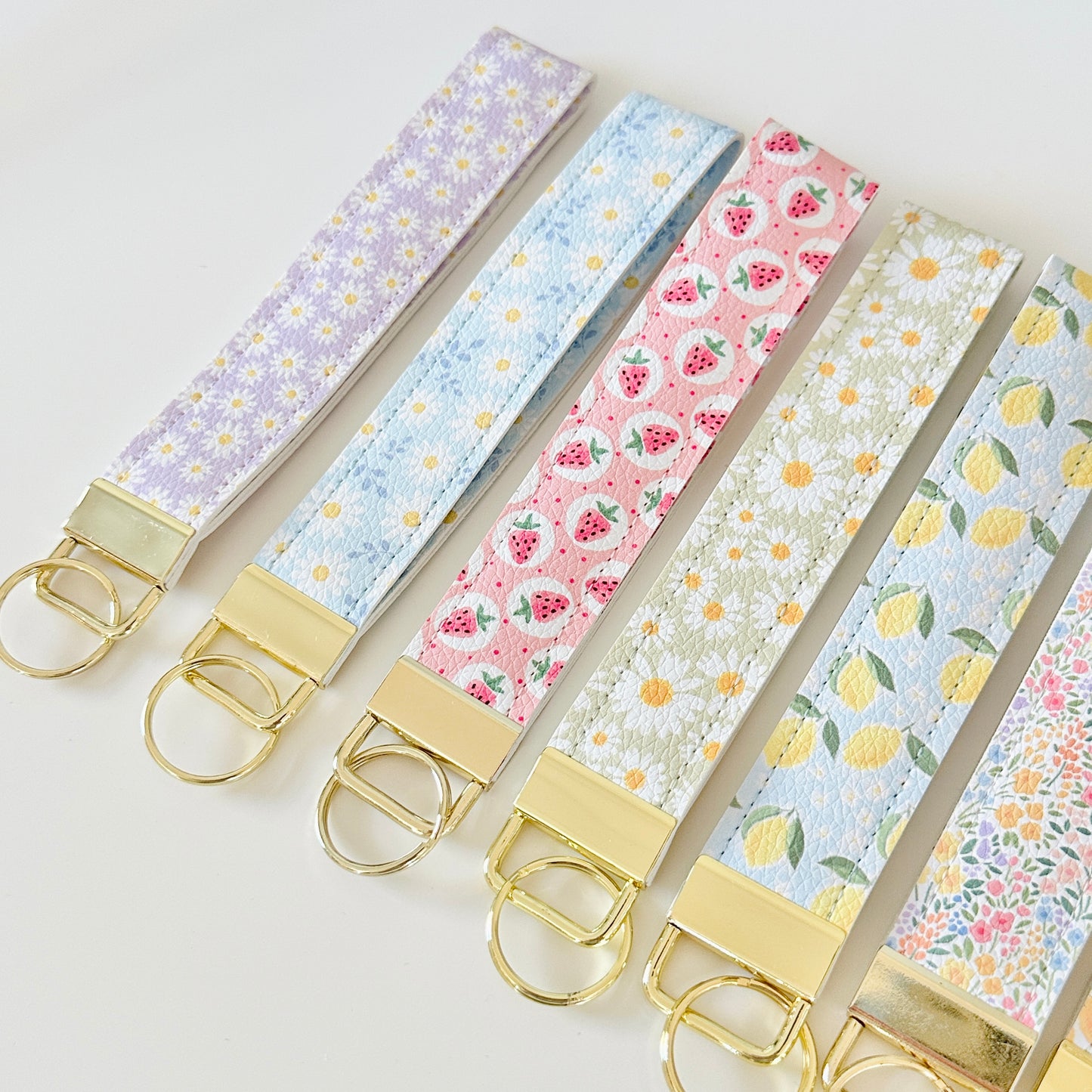 Set of floral patterned keychains with gold clasps on a light background