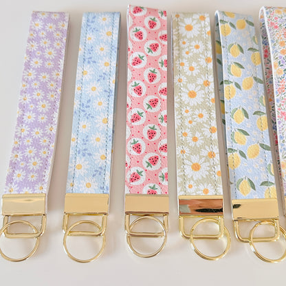 Set of keychains with colorful patterns and gold clasps on a white background