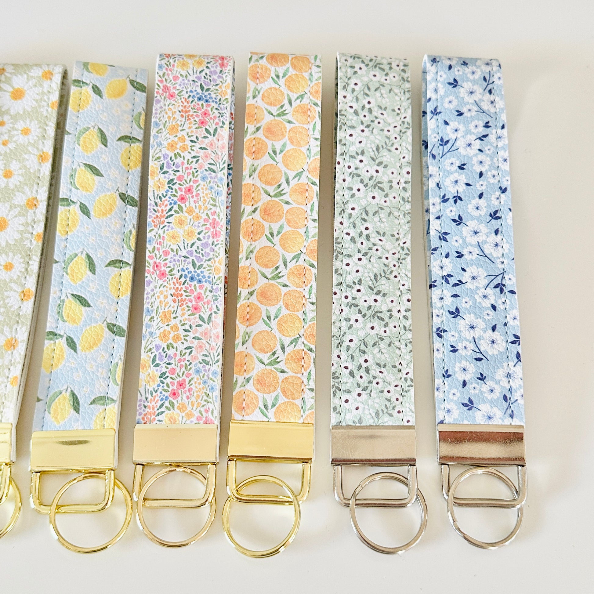 Set of floral and patterned keychains with gold clasps on a light background
