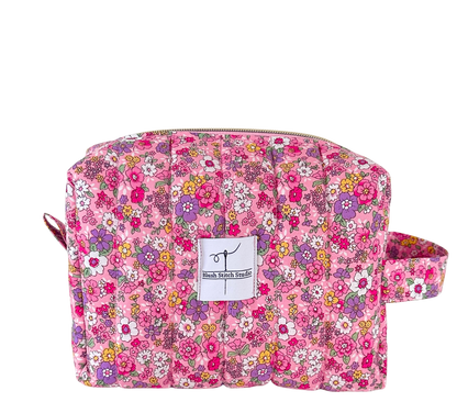 Floral patterned quilted pouch with a visible brand label on a white background