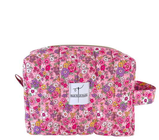 Floral patterned quilted pouch with a visible brand label on a white background
