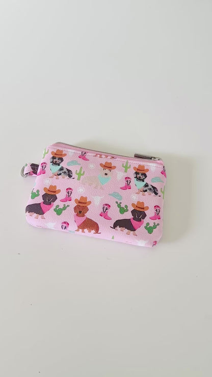 Pink coin purse with dog pattern on a white background