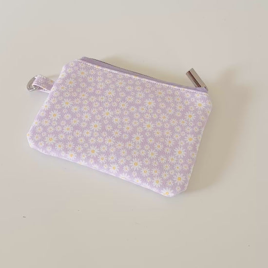 Purple floral-patterned coin purse with coins on a light gray background