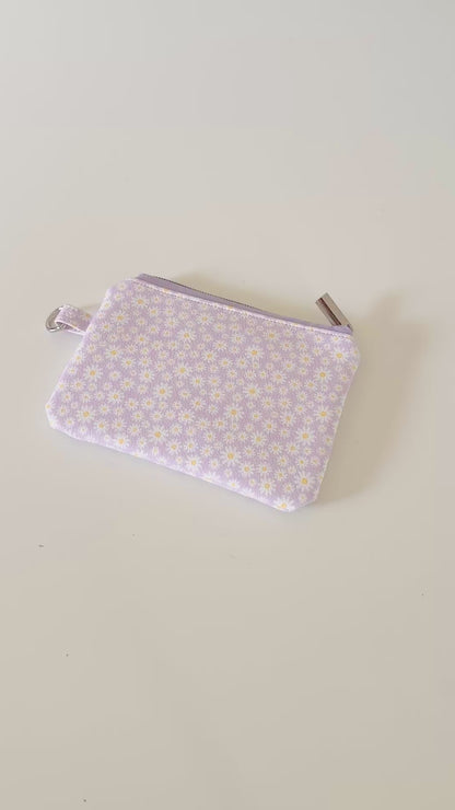 Purple floral-patterned coin purse with coins on a light gray background