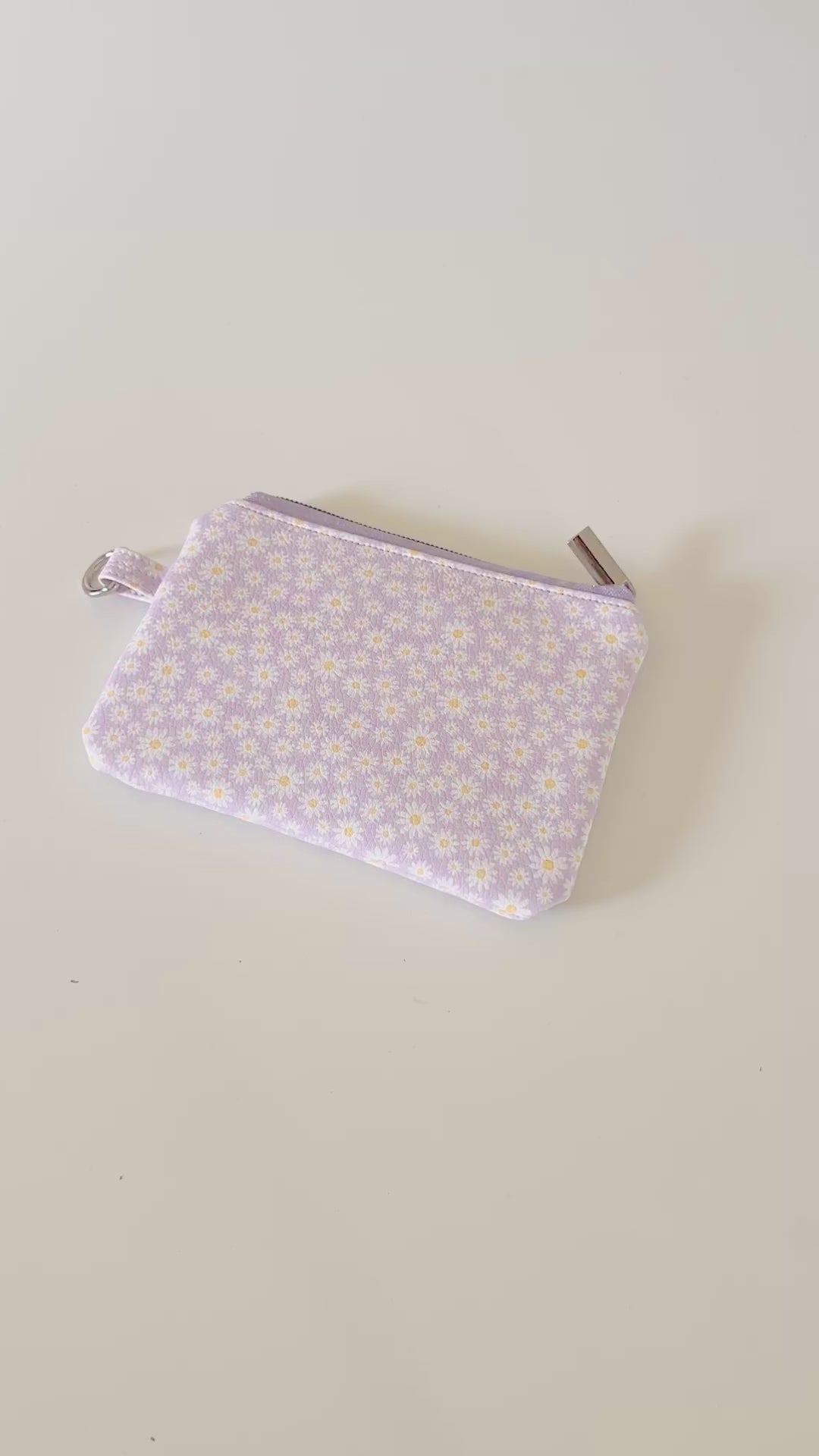 Purple floral-patterned coin purse with coins on a light gray background