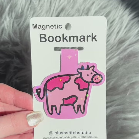 Pink cow-shaped magnetic bookmark on a Blush Stitch Studio card against a gray fur background