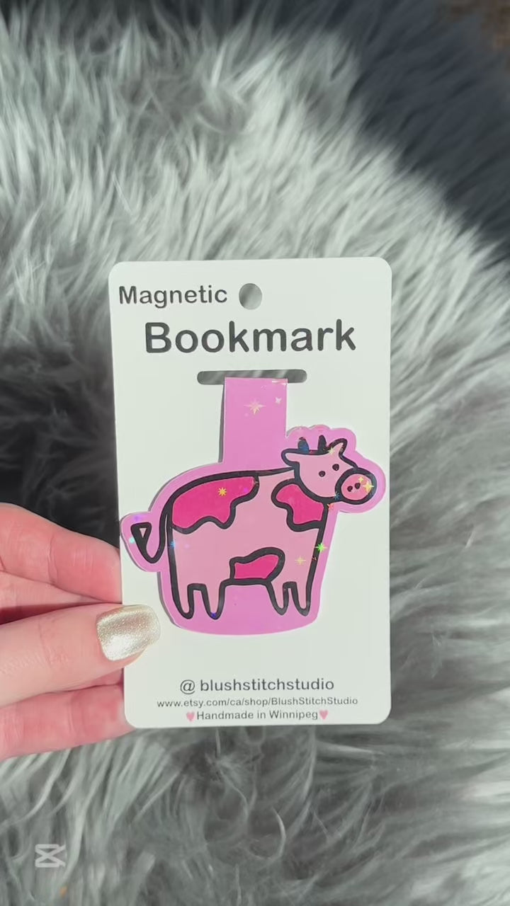 Pink cow-shaped magnetic bookmark on a Blush Stitch Studio card against a gray fur background