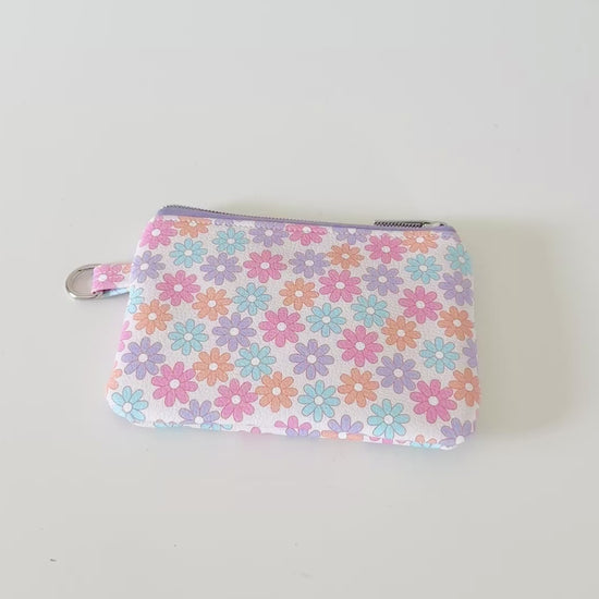 Floral patterned coin purse with cards and coins on a white background