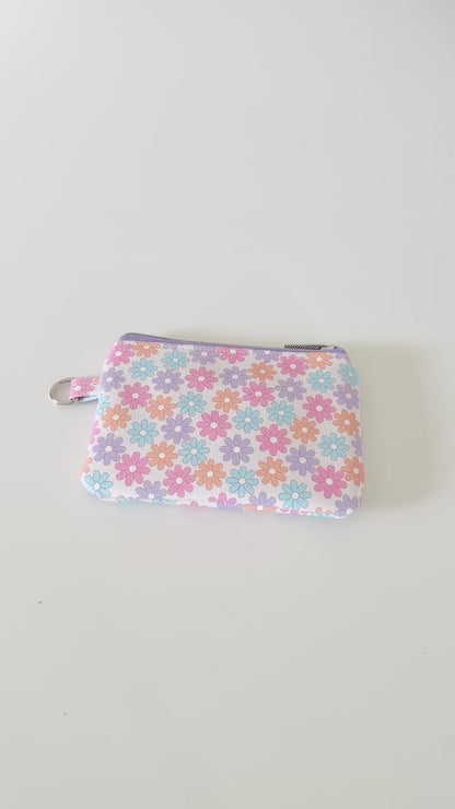 Floral patterned coin purse with cards and coins on a white background