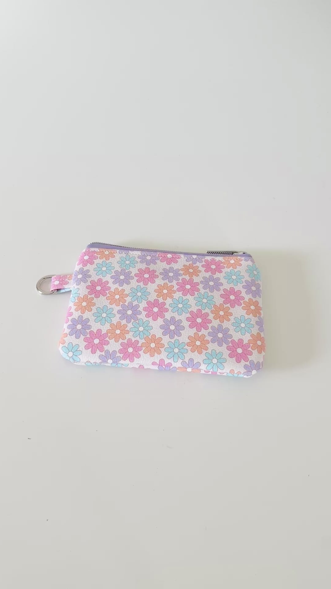 Floral patterned coin purse with cards and coins on a white background