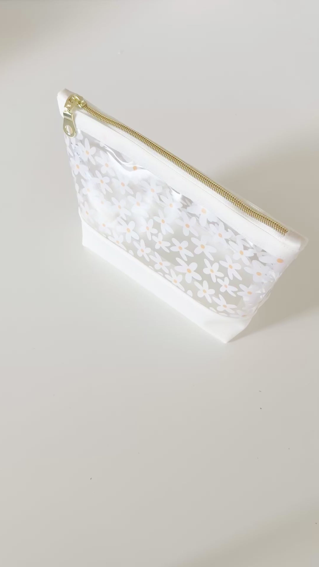 Clear pouch with white floral pattern on a light gray background
