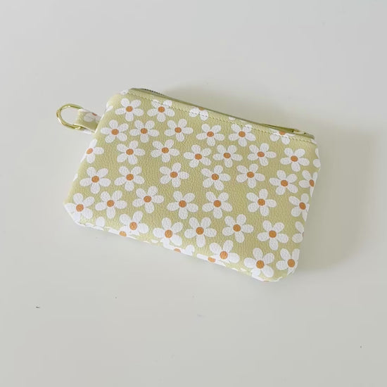 green Floral daisy patterned coin purse with coins on a light background