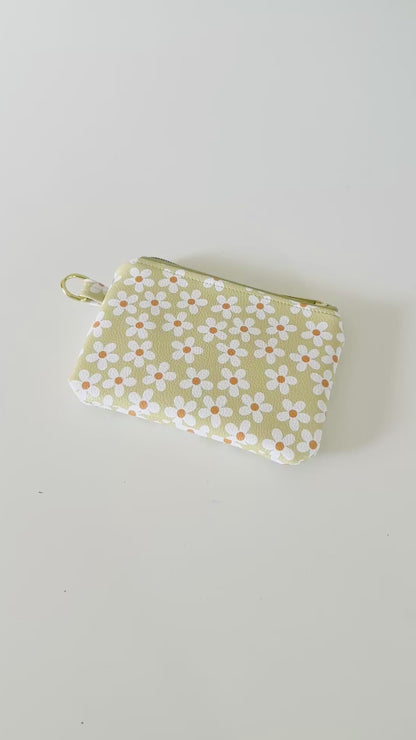 green Floral daisy patterned coin purse with coins on a light background