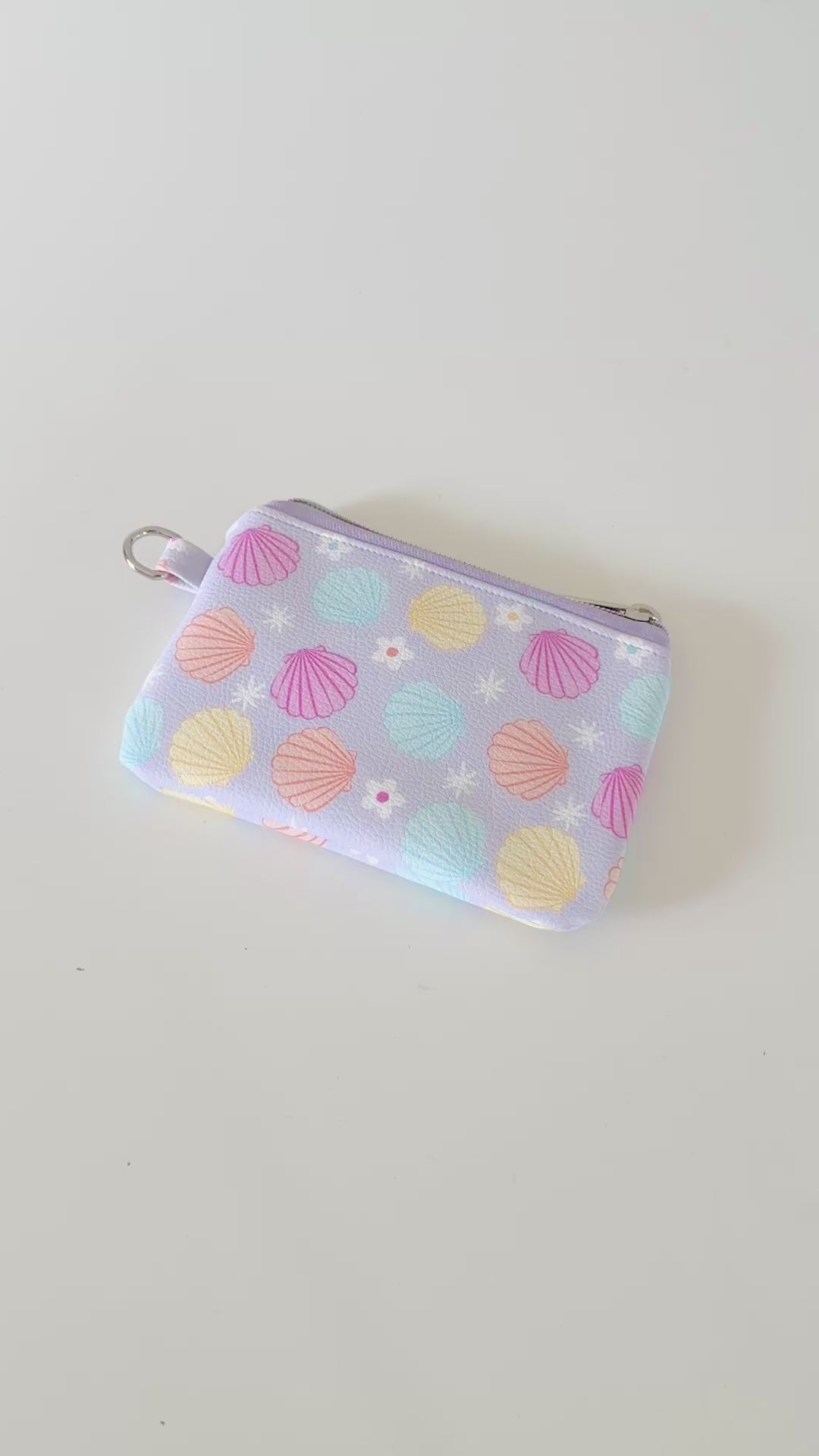 purple vegan leather coin purse with seashell pattern on a white background