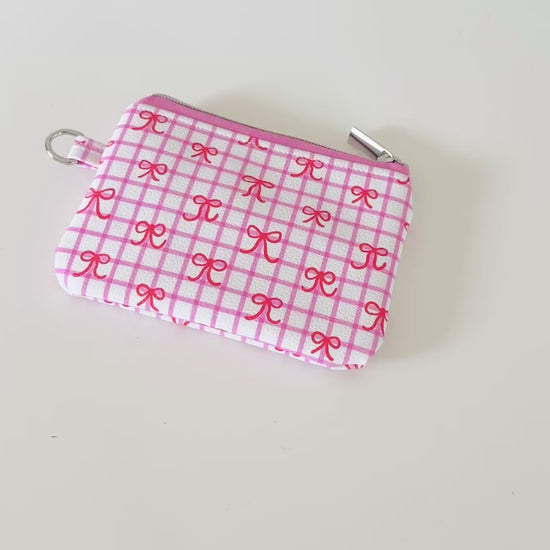 Pink checkered coquette vegan leather coin purse with red bows on a white background