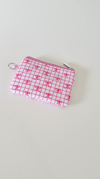 Pink checkered coquette vegan leather coin purse with red bows on a white background