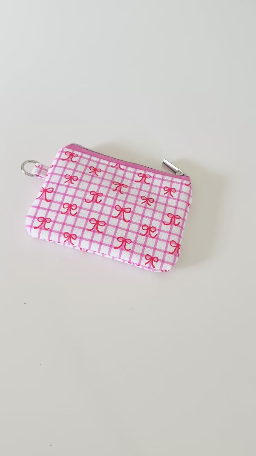 Pink checkered coquette vegan leather coin purse with red bows on a white background