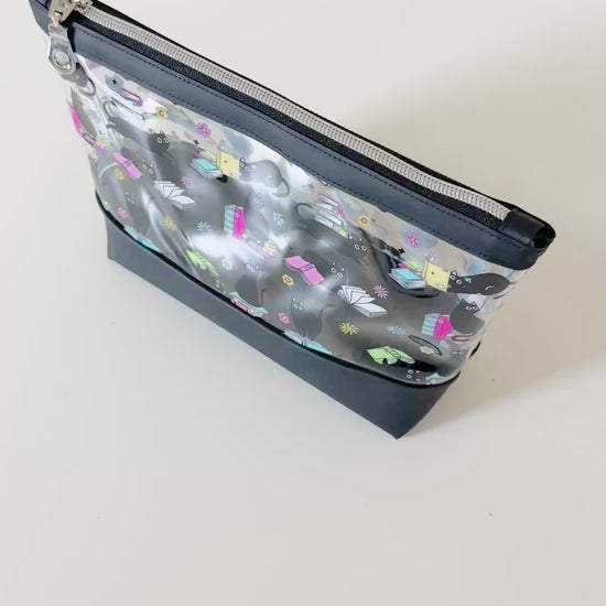 clear makeup bag with a black cat and book pattern