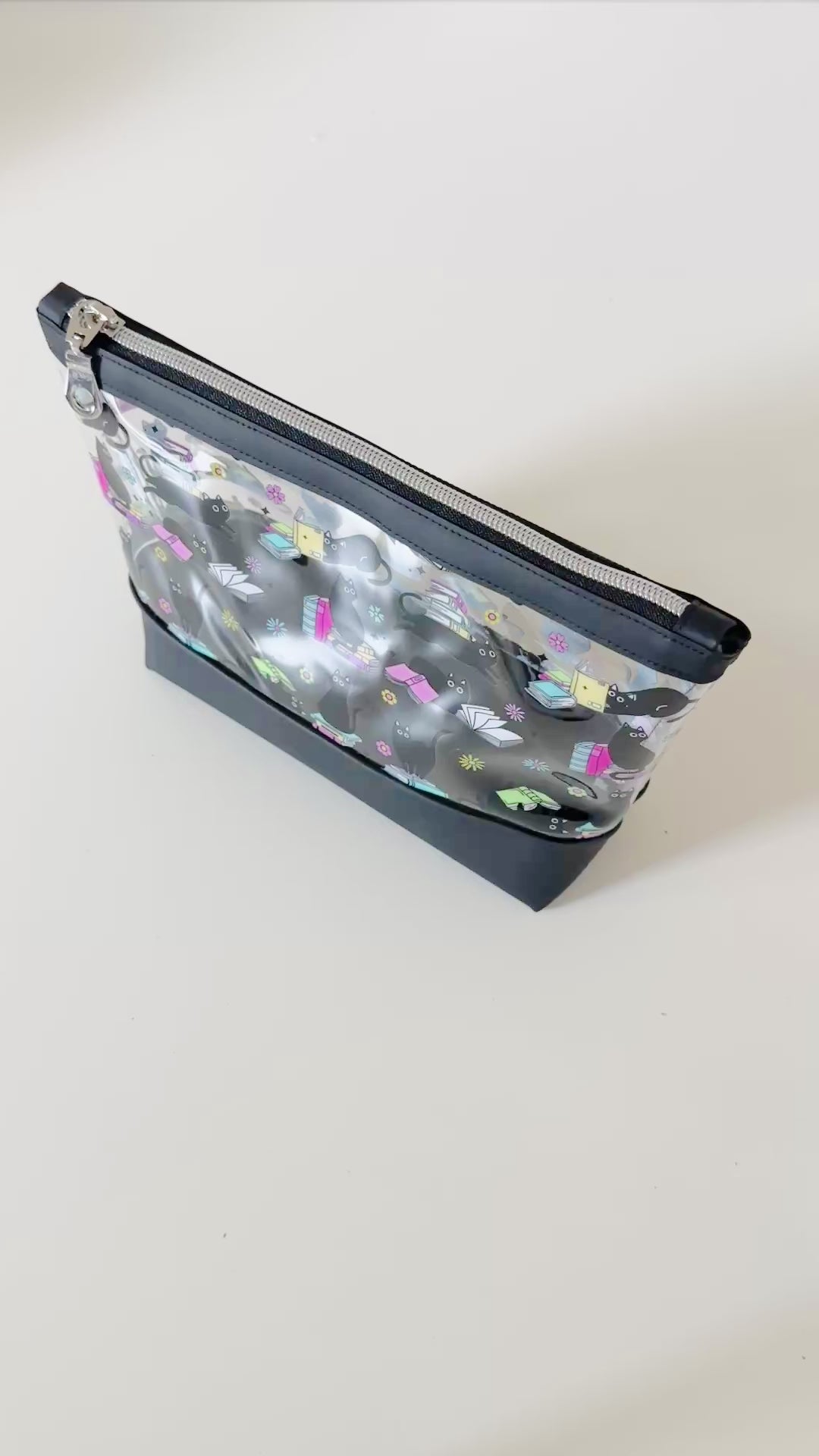 clear makeup bag with a black cat and book pattern