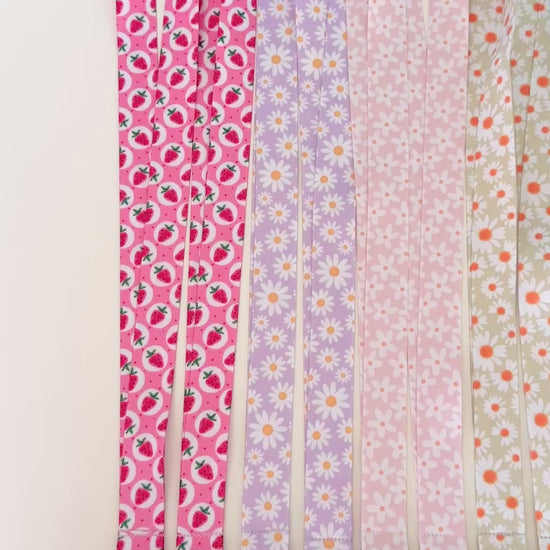 Set of colorful patterned lanyards hanging on a rack against a white background